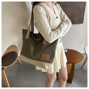 Dettaglio della borsa tote in tela verde e beige con inserto in pelle sulla spalla
