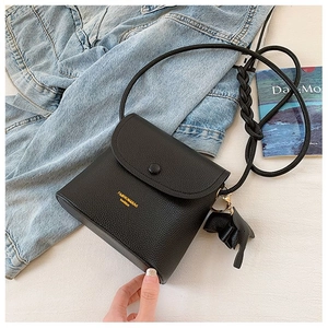 Detail of black pebbled leather crossbody bag with logo and cute elephant charm
