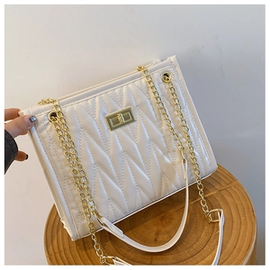 Detailed view of white quilted shoulder bag with V-shaped stitching and gold chain strap