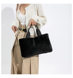 Detail of black faux fur tote bag with plush pompom pendant and nylon web handles