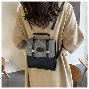 Rückansicht eines grauen Denim-Leder-Rucksacks, getragen über einem beigen Mantel