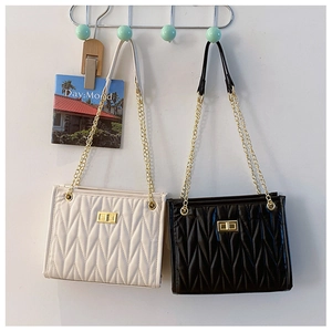 Close-up of beige and black V-quilted faux leather bags with golden metal chain straps