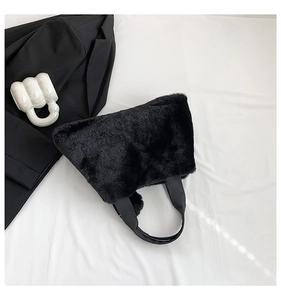 Close-up of black faux fur tote bag with textile handles on a minimalist background