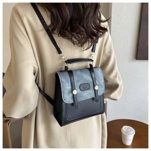 Détail d'un sac à dos chic en cuir bicolore avec logo métallique sur un manteau beige élégant