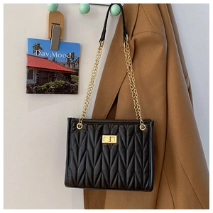 Detail of black matelassé shoulder bag with golden twist lock and chain strap hardware