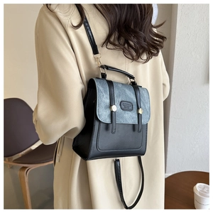 Detail des Retro-Minirucksacks mit grauer Klappe und schwarzem PU-Leder am Modell
