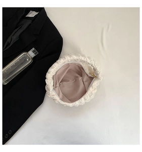 Detailed close-up of white cloud-style handbag with pleated bubble texture and zip closure