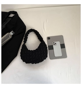 Flat lay of black cloud bubble bag with puffy texture and curved hobo design on white fabric