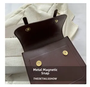 Detail view of the elegant golden magnetic clasp on a premium brown leather bag