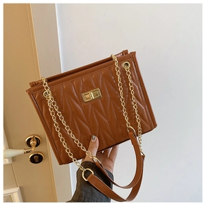 Detail of brown quilted leather bag featuring gold chain strap and turn-lock closure