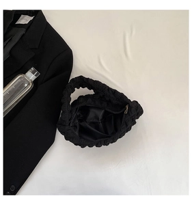 Close-up of black cloud pleated handbag with bubble texture and metal zipper detail