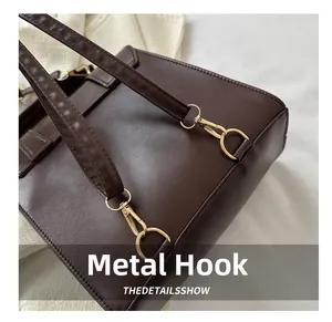 Detail of dark brown leather backpack showing gold hardware hooks and fine stitching