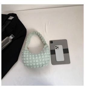 Detailed top view of mint green bubble texture handbag with everyday essentials