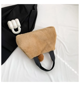 Close-up of fluffy brown faux fur handbag with black strap and matching pompom pendant