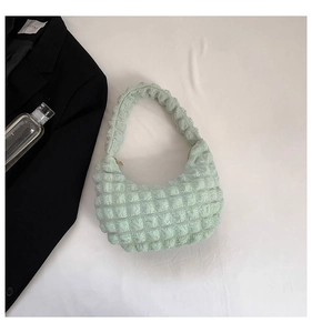 Close-up of mint green pleated bubble fabric handbag with textured crescent design