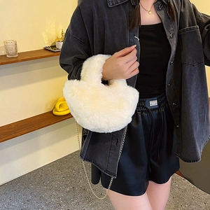 Sac seau en peluche blanche avec chaîne dorée, porté par un mannequin en intérieur doux