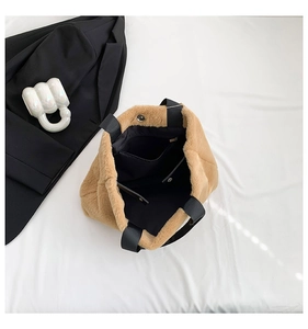 Interior detail of plush brown tote bag showing black lining, zipper pocket and magnetic buckle