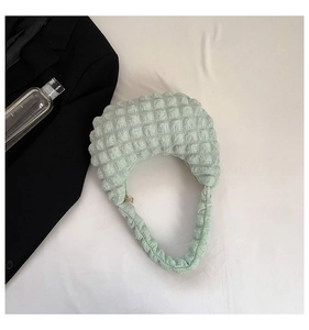 Flat lay of mint green bubble texture handbag with integrated handle on white background