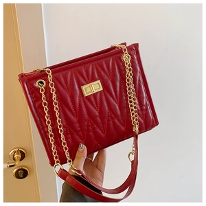 Close-up of red V-quilted leather bag with gold chain strap and square metal turn-lock
