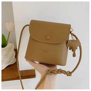 Detail of camel PU leather crossbody bag with lychee texture and elephant charm