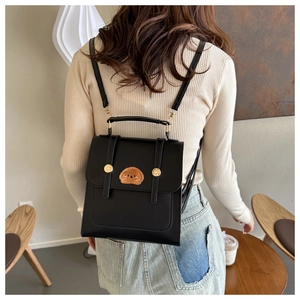 Detail of black PU leather backpack with gold hardware and cute puppy embroidery