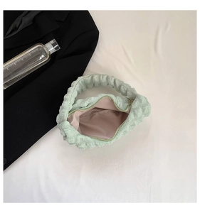 Detail of mint green cloud pleated handbag showing pink lining and internal pocket