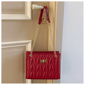 Detail of red quilted crossbody bag with golden twist lock hanging on a door handle