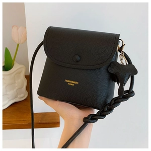 Detail of black lychee grain PU leather crossbody bag with knot charm and metal logo