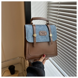 Detail view of retro color-block handbag with brown leather and blue textured flap