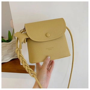 Detail of ginger yellow PU leather crossbody bag with braided strap and elephant charm