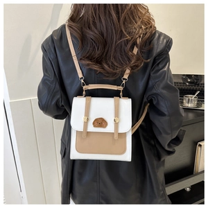Detail of small color-block backpack with cute bear patch and adjustable straps on model