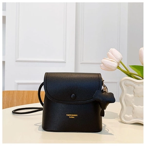 Detail of black small crossbody bag with litchi grain and cute dog charm pendant