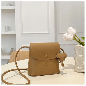 Detailed view of brown lychee leather crossbody bag with cute elephant charm pendant