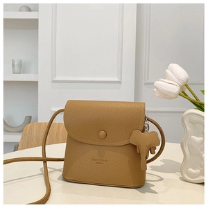 Detail of light tan lychee grain crossbody bag with cute elephant charm and round buckle