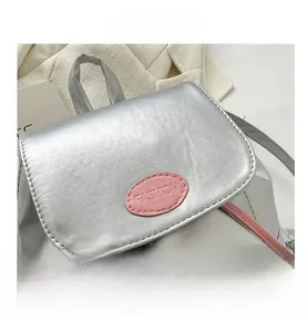 Dettaglio dello zaino argento metallizzato con etichetta FASHION rosa e coulisse