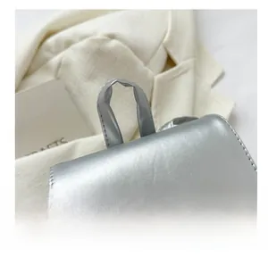 Dettaglio ravvicinato del manico comodo su zaino in pelle metallizzata argento capiente