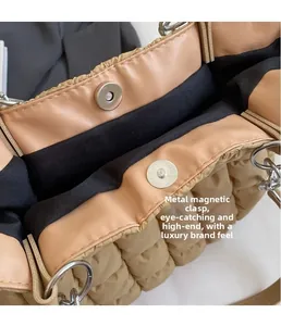 Detail of silver magnetic snaps on a khaki quilted puffer tote bag with black lining