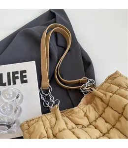 Detail of khaki quilted tote bag with silver chain strap and smooth leather accents