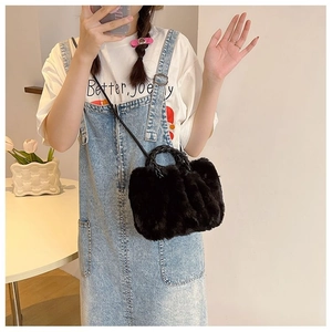 Detail of plush black faux fur handbag with woven handle and slim leather crossbody strap