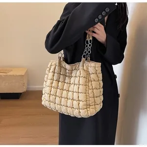 Quilted beige puffer tote bag with silver chain straps shown in a lifestyle setting