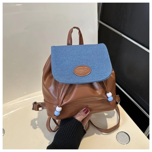 Détail du mini sac à dos en similicuir marron et rabat en denim bleu avec cordon