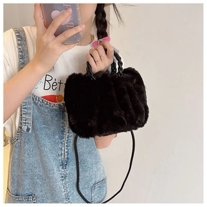 Detailed view of the black plush cloud bag with woven handle and soft faux fur texture