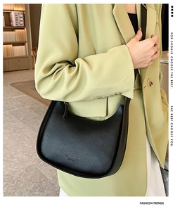 Side view of a black crescent shoulder bag on a lime green blazer with logo detail