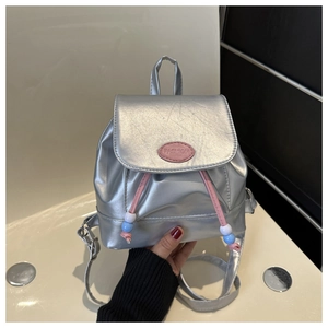 Vue détaillée du mini sac à dos argenté avec étiquette rose et cordon à perles colorées