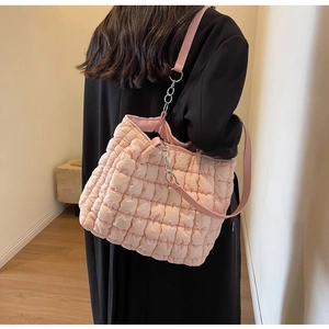 Detail of pink quilted puffer tote bag with silver chain and soft padded fabric texture