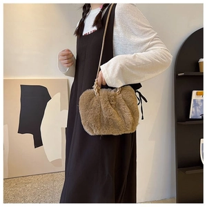 Detail view of brown faux fur handbag with stylish pleated design and braided handle texture