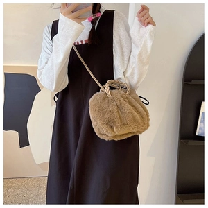 Detail of plush brown shoulder bag featuring woven handles and soft faux fur texture