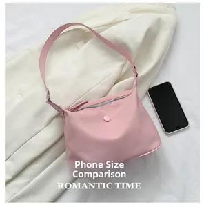 Pink nylon hobo bag shown with a smartphone for size reference on a white fabric background