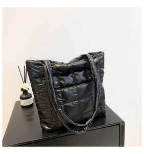 Détail d'un sac cabas rembourré noir brillant avec sa bandoulière large assortie