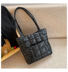Gros plan d'un sac cabas matelassé noir avec coutures carrées sur un canapé